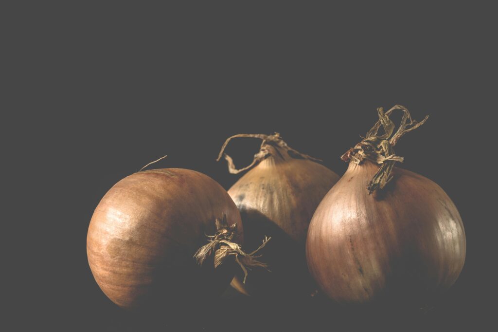 A still life photograph of fresh organic onions with a black backdrop, ideal for food photography and culinary uses.
